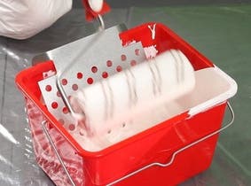 Une personne qui trempe son rouleau dans la peinture