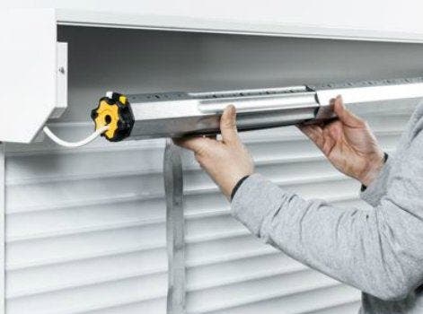Photo illustrant un homme installant la motorisation d'un volet