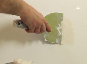 Une personne qui répare les imperfections d'un mur