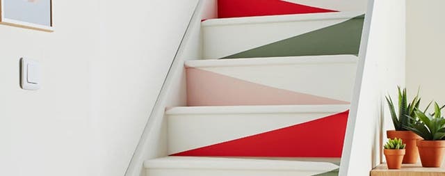 Photo d'un escalier coloré avec des fleurs sur le meuble d'entrée
