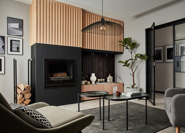 Photo d'un salon avec cheminée noir et décoration bois au dessus. 