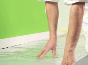 Une personne qui protège son sol avec une bâche de protection