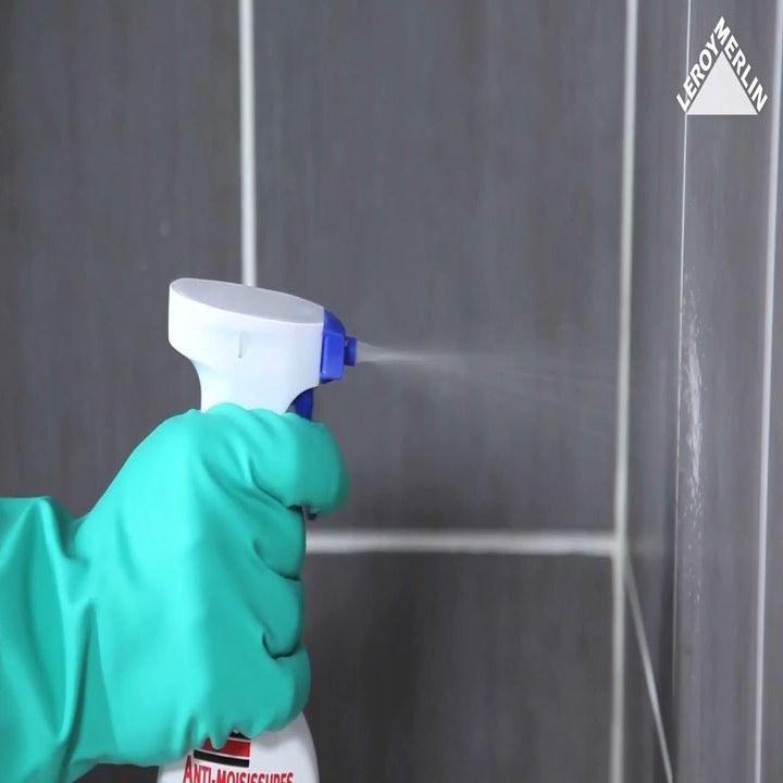 photo d'un homme qui élimine les moisissure des joints de carrelage de salle de bains