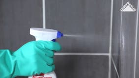 photo d'un homme qui élimine les moisissure des joints de carrelage de salle de bains