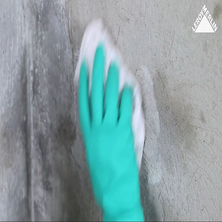 photo d'un homme frottant un mur pour éliminer les taches d'humidité