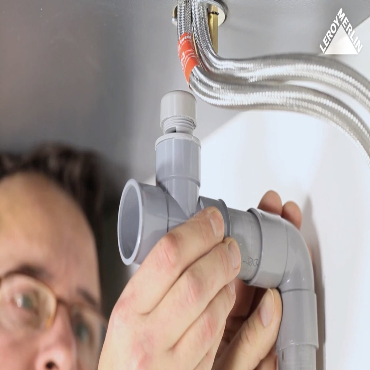Photo homme installant PVC évacuation salle de bain
