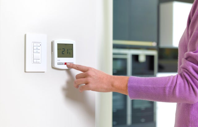 Photo d'une femme utilisant un thermostat. 