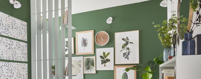 parede verde com quadros e um relógio de madeira