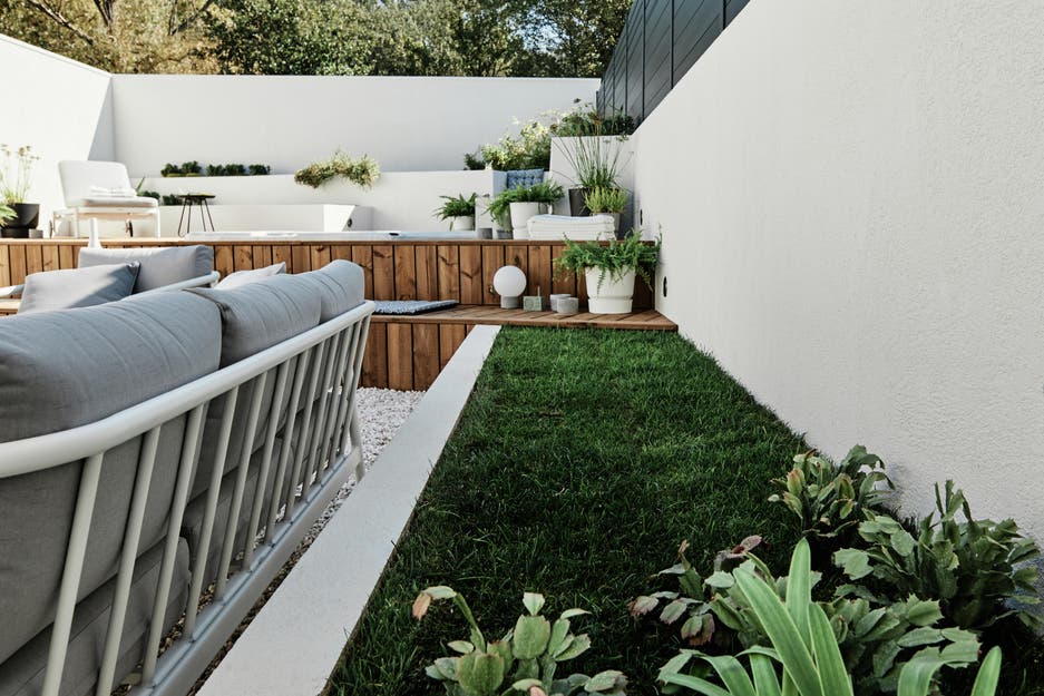photo d'une longue jardinière maçonnée, peinte en blanc et engazonnée