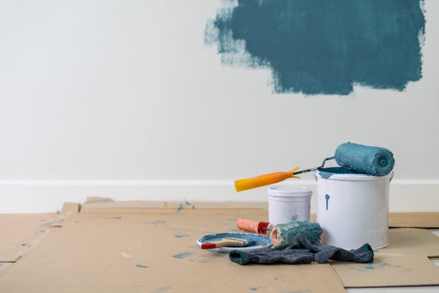 Photo d'un rouleau à peinture avec de la peinture bleue dessus, posé sur un pot à peinture. 