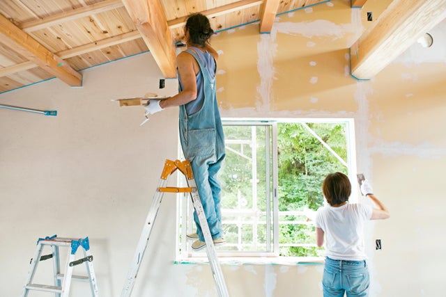 Photo de deux femmes peignant un plafond et un mur. 