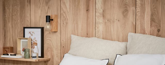 Photo Leroy Merlin d'une tête de lit en bois avec des coussins beiges et blancs. 