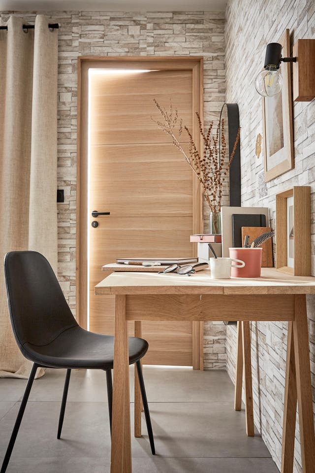 Photo Leroy Merlin d'un bureau ambiance nature avec une porte en bois clair et les murs en briques beiges. 