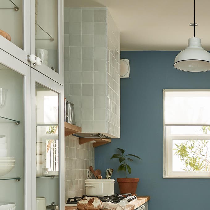 Photo d'une cuisine avec des meubles gris, un mur bleu et un plan de travail en bois. 
