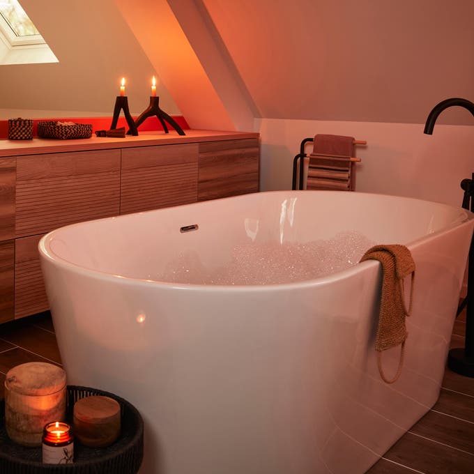 Photo Leroy Merlin d'une baignoire ilot dans une suite parentale avec des bougies allumées. 