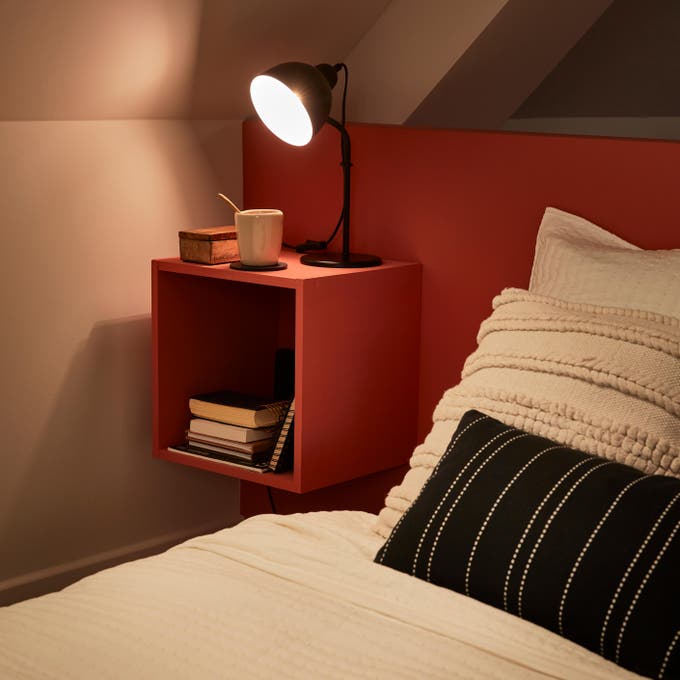 Photo Leroy Merlin d'une table de chevet avec une lampe de chevet allumée dessus. 