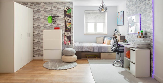 Dormitorio juvenil con zona de estudio, alfombras y puffs. 