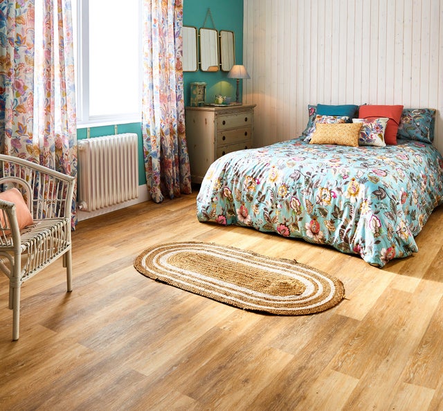 Dormitorio vintage con suelo de madera, pared con friso blanco y ropa de cama de flores. 