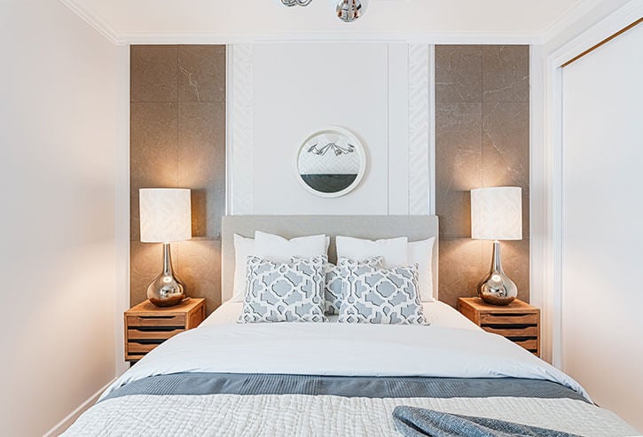 Quarto com cama de casal e duas mesas de cabeceira, um candeeiro de teto, espelho, candeeiros de mesa, cortinados brancos e tapete
