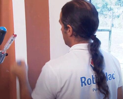 Senhor a pintar os barrotes de madeira com tinta branca para madeira