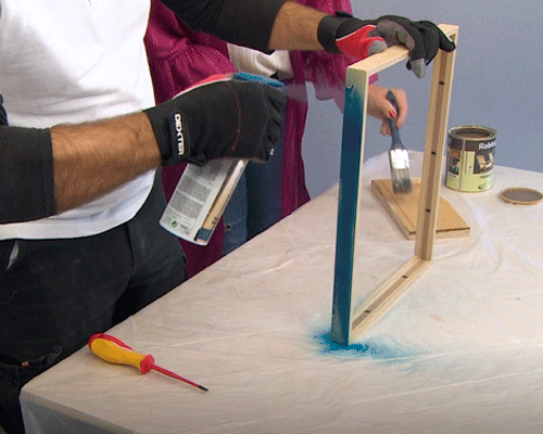 Senhor a pintar a moldura com uma lata de tinta em spray azul