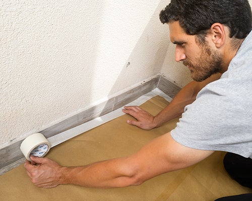 senhor a proteger o chão com papel para não sujar com tinta