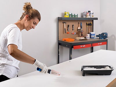 senhora a pintar porta com tinta branca a usar um rolo