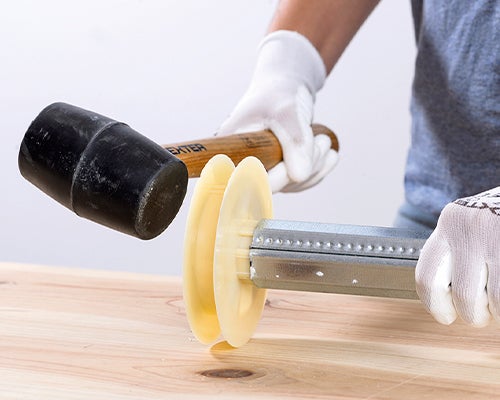 pessoa com luvas de proteção a substituir uma polia com a ajuda de um maço.