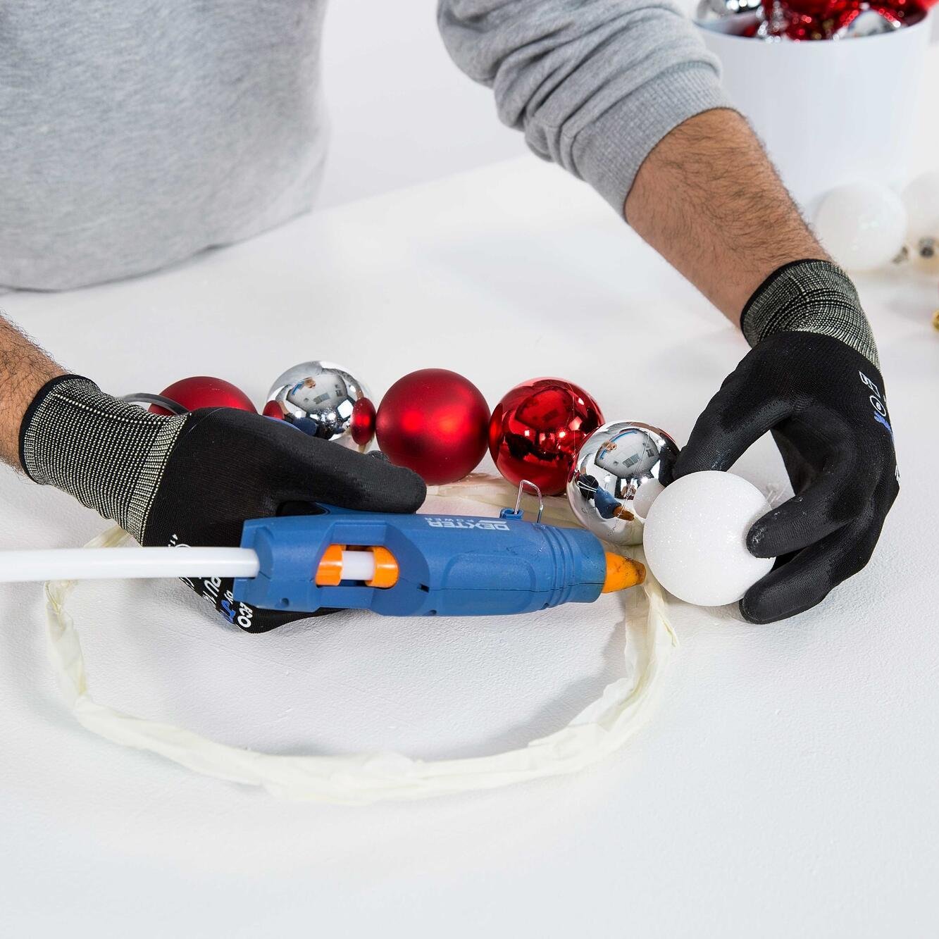Com a pistola de colar cole as bolas de Natal ao redor do círculo metálico