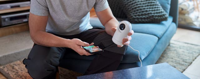 pessoa a colocar uma câmara de vigilância ligada ao telemóvel