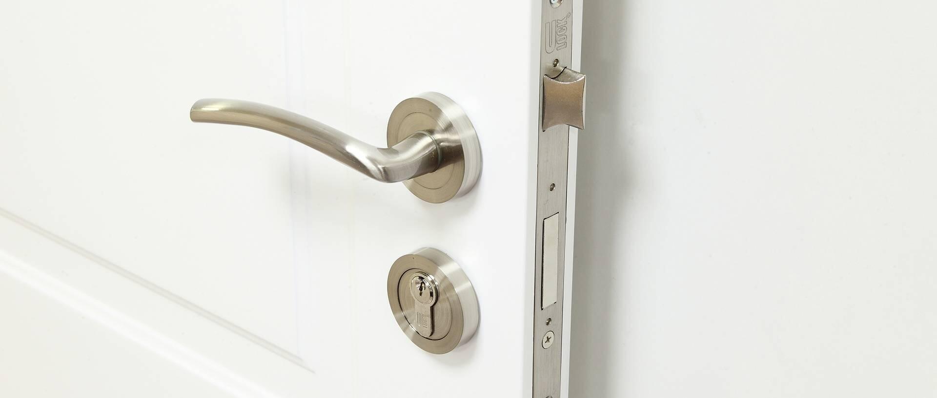 Imagem de uma porta branca com ênfase na fechadura de uma porta de interior