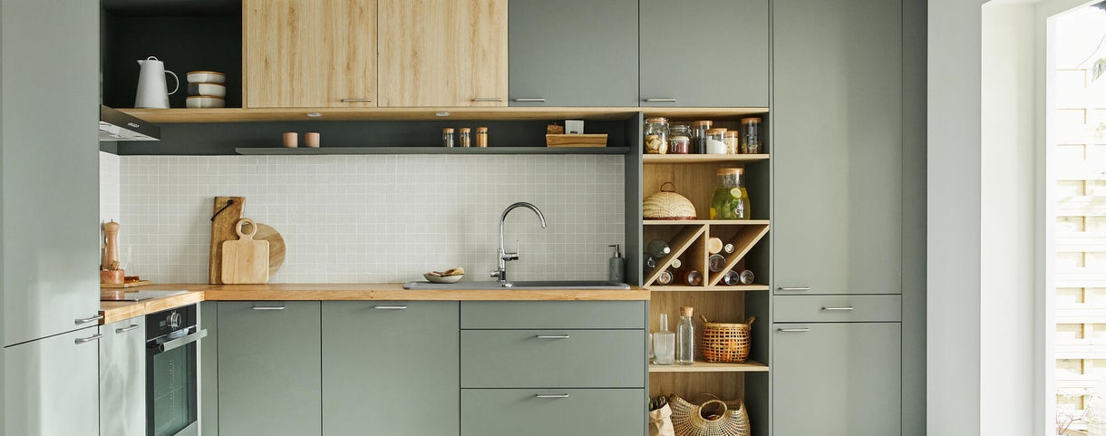 La cocina tiene un estante de madera y paneles de pared verdes