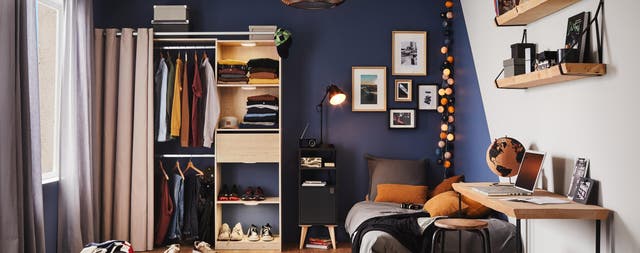 Dormitorio juvenil con pared pintada de azul oscuro y muebles de madera. 