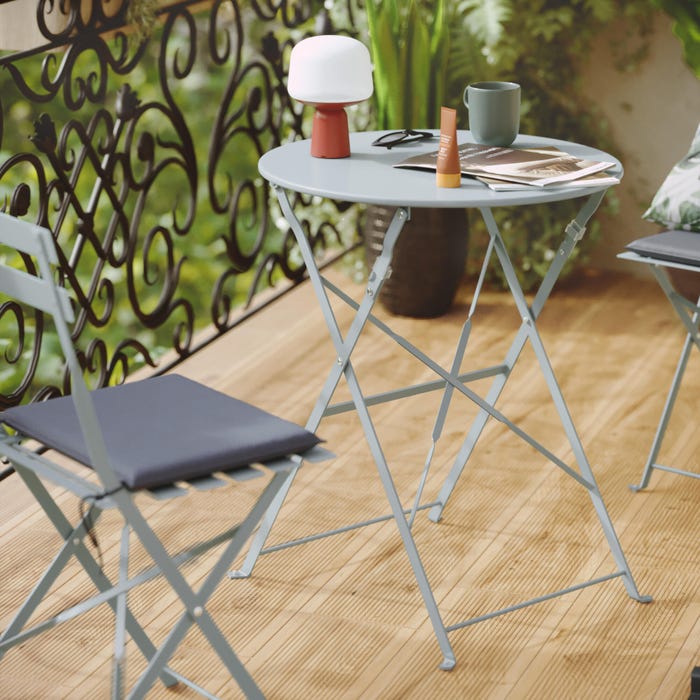 uma mesa de jardim para 2 pessoas com 2 cadeiras azuis, material floral
