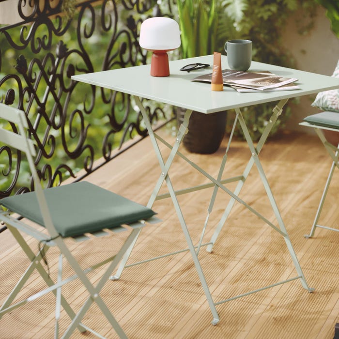 uma mesa quadrada de jardim para 2 pessoas com 2 cadeiras verdes, material flora