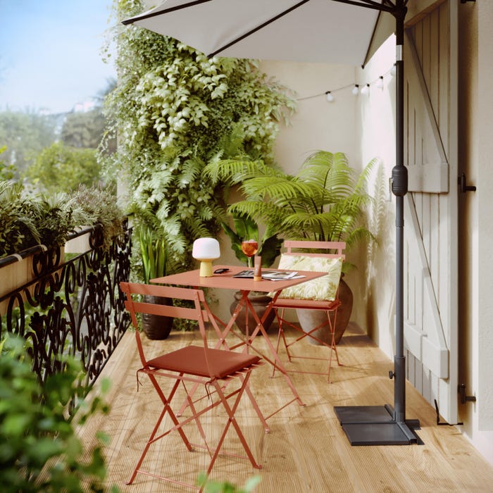 cenário de jardim com mesa quadrada e duas cadeiras laranja, além de guarda-chuva e material vegetal