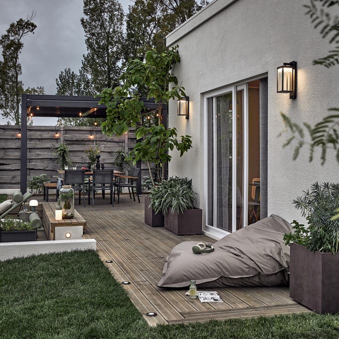 photo d'un grand pouf extérieur sur la terrasse en bois avec des appliques murales extérieures allumées