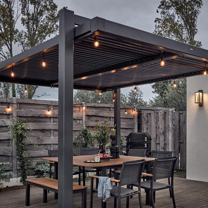 photo d'une pergola en aluminium gris anthracite avec des guirlandes extérieures allumées