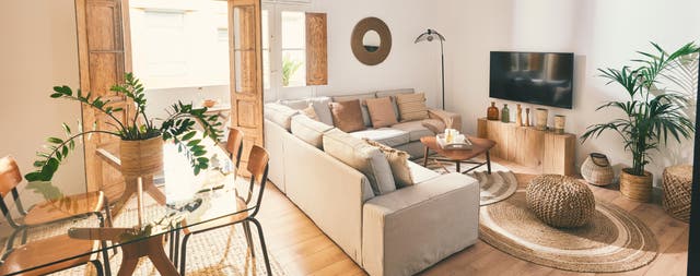 Salón de una casa moderna con sofá rinconero en beige y decoración en madera y fibras. 