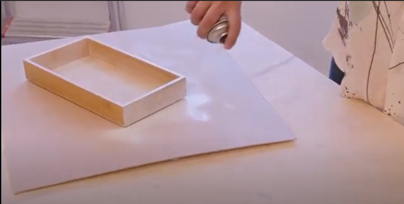 imagem de uma pessoa a pintar o suporte de talheres com um spray branco