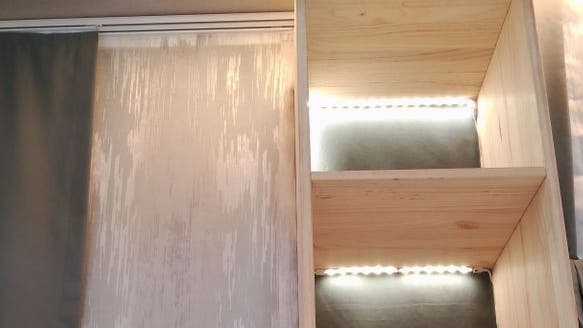 Estantes de madera con iluminación LED dentro del armario, la luz