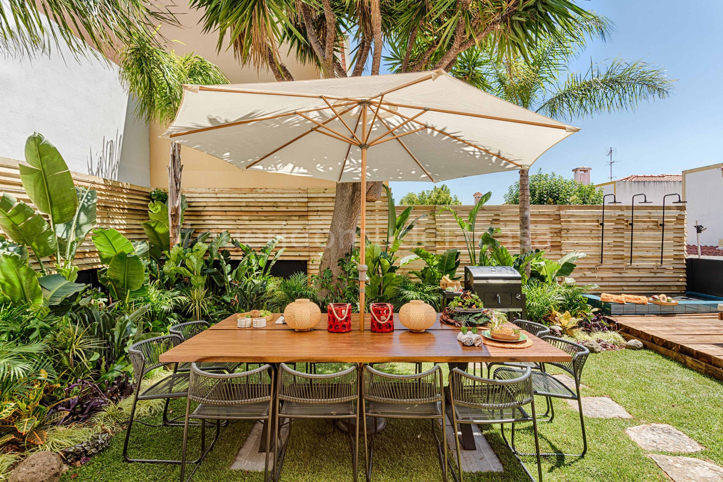 uma mesa grande no jardim com um chapéu de sol 