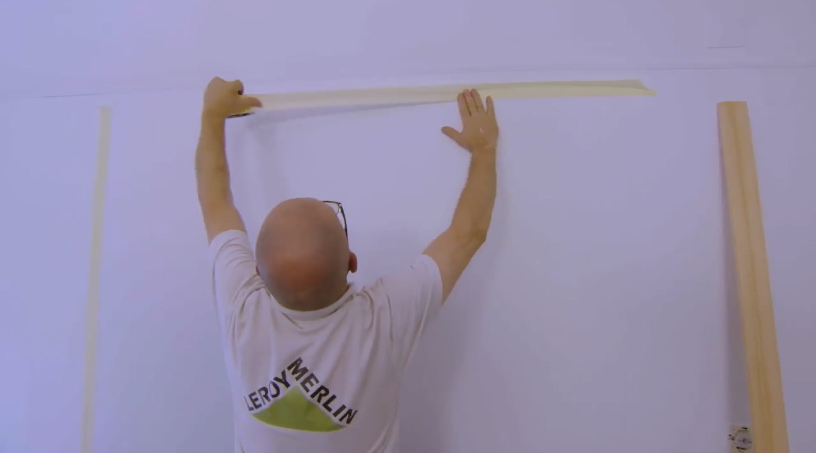 pessoa a colocar fita de pintor a delimitar o quadro