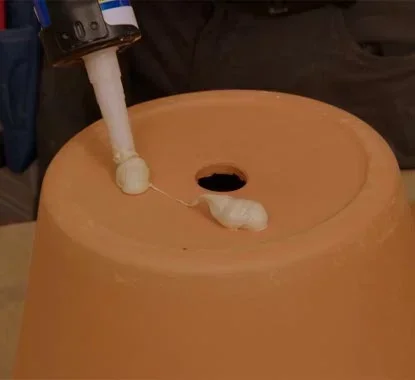 Aplicação de cola de montagem na parte inferior de um vaso de barro
