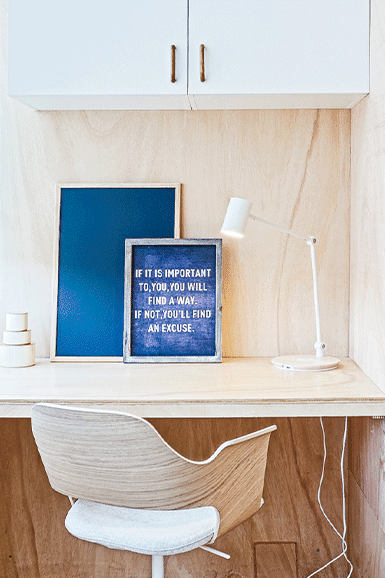 Varanda transformada em escritório, com arrumação, banco e decoração com quadro de frase inspiracional 