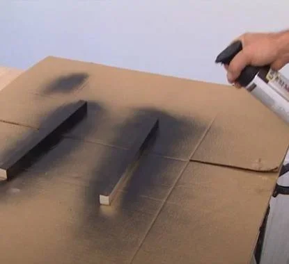 Senhor a pintar as ripas de madeira com uma tinta spray preta