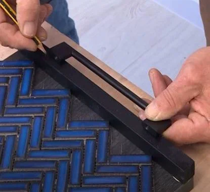 Senhor a fazer a medição de onde irá furar o tabuleiro com a aparafusadora para colocar os puxadores