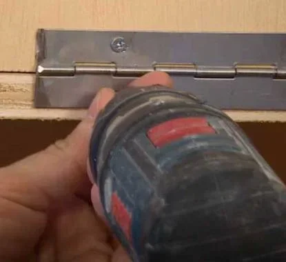 Aparafusar a dobradiça na parte interior da peça