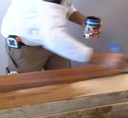 Senhor a aplicar velatura nas prateleiras de madeira rustica