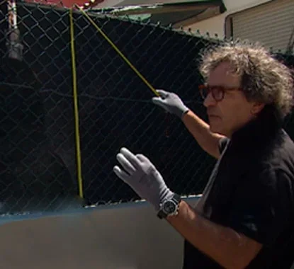 Senhor a medir com uma fita métrica a vedação de metal verde